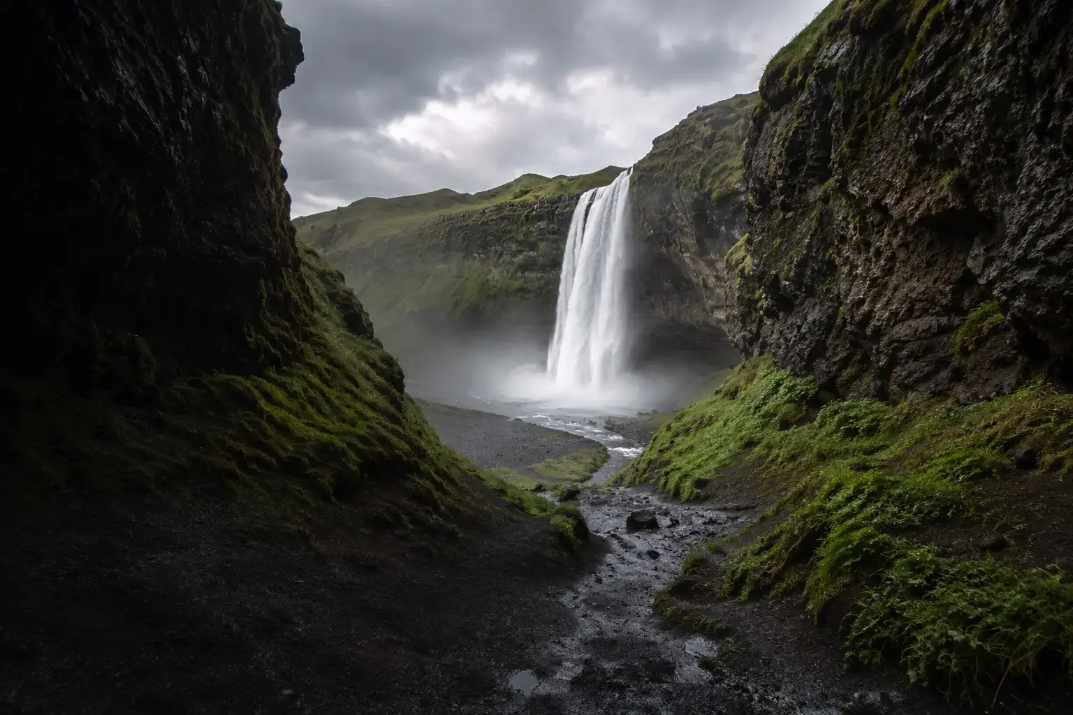 Adventure Quest artwork for the Waterfalls & Wild Trails adventure: a waterfall at the end of a narrow green canyon.