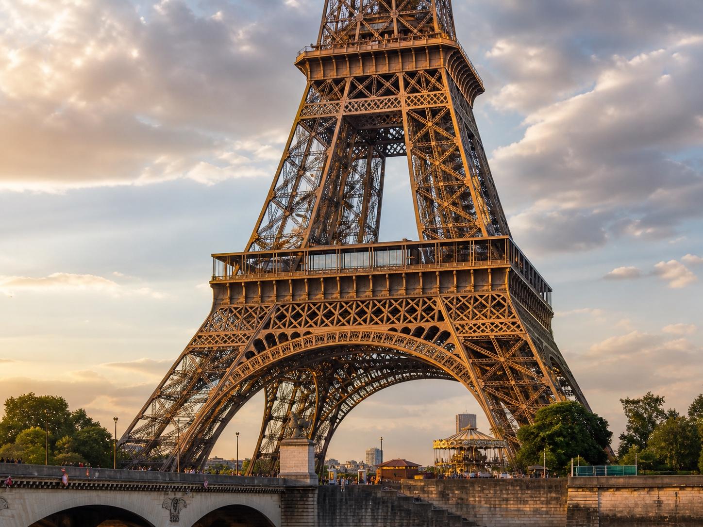 The Eiffel Tower at golden hour seen from across the Seine, with people crossing the Pont d’Iéna below.